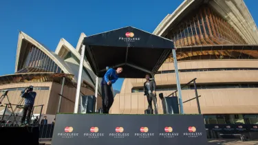 Two men playing golf under a Mastercard stand outside the Sydney Opera House.
