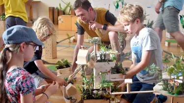 A man helping kids build a house model.