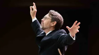 Andrey Boreyko stands with arms outstretched.