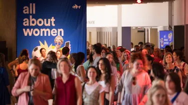 Audiences members leave a Sydney Opera House venue with a large poster saying "All About Women"