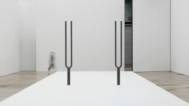Two large tuning forks stand on the floor.
