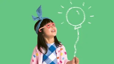 An Asian girl holding a pretend balloon which is glowing.