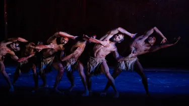 A group of dancers performing a traditional Aboriginal dance on a stage.