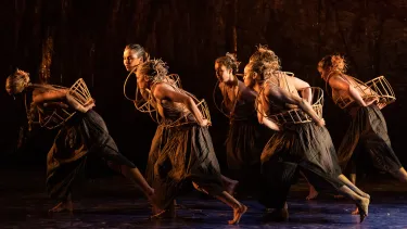 A group of dancers performing a traditional Aboriginal dance on a stage.