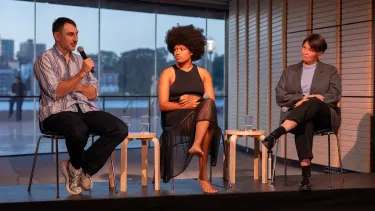 Three artists speak on stools.