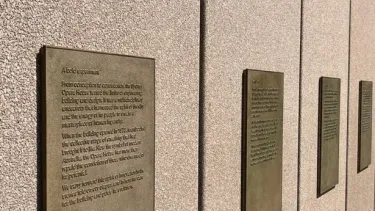 A row of plaques with raised text on a wall.