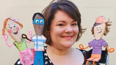 A woman in black dress holding three puppets.