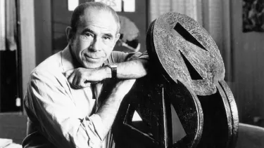 Dennis Wolanski OAM standing with angled wheels of fortune.