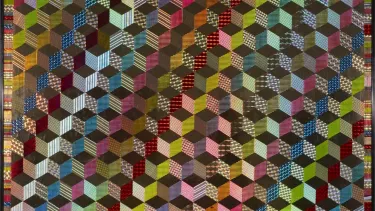 A colorful quilt composed of squares and triangles, displaying a harmonious blend of bright hues and geometric patterns.