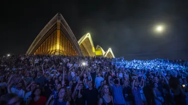 Concertgoers at a show outside in front of the Sydney Opera House.