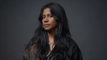 A Southern Indian woman in her 30s with long brown hair looks at the camera.