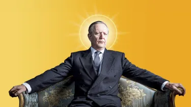 A man in a suit sits on an ornate couch, arms spread across the backrest, with a glowing halo effect behind his head, against a yellow background