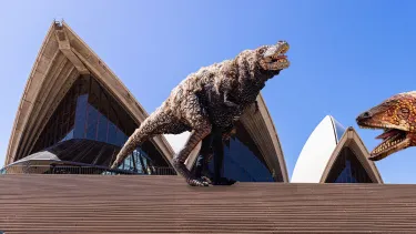 Three dinosaur puppets on the Sydney Opera House steps under a clear blue sky.