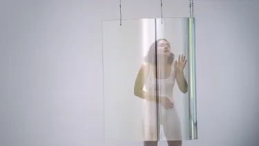 A performer interacting with a translucent screen in an art gallery.
