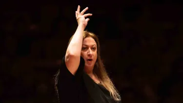 Simone Young conducts with one hand raised.