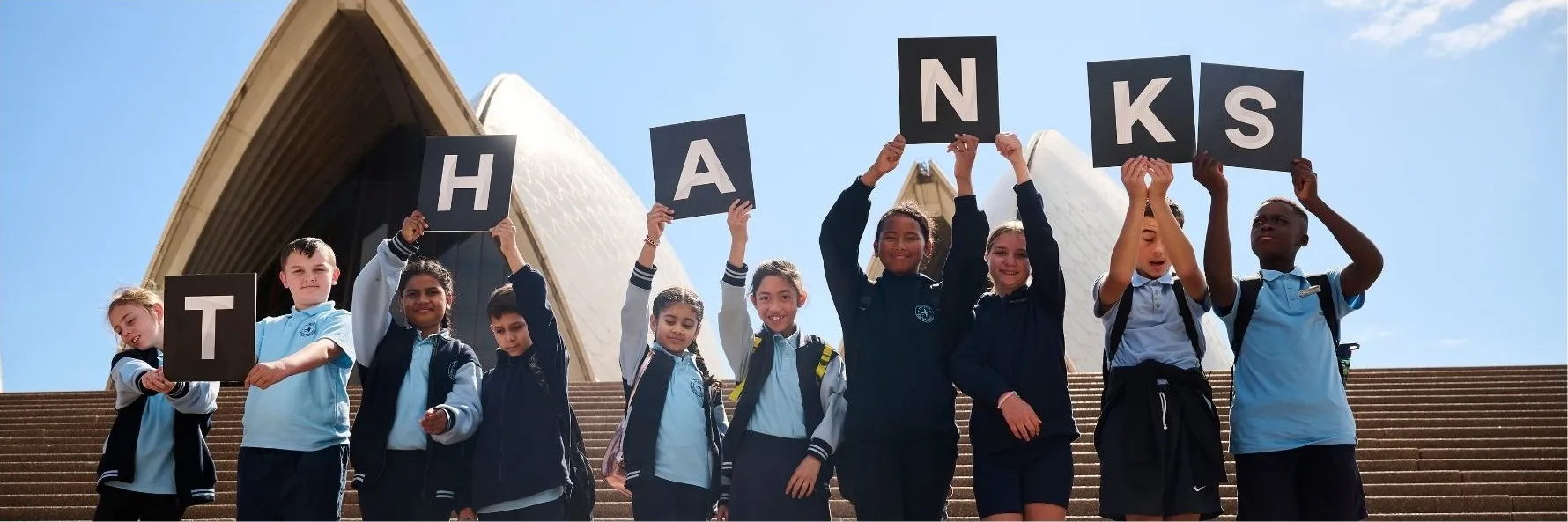 School children holding letters spelling thanks.