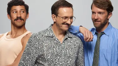 Three men stand side to side smiling.