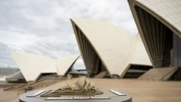 Bronze tactile model of the Sydney Opera House photographed in front of the Opera House sails.