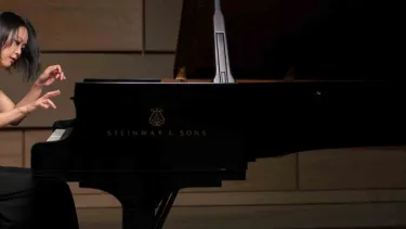 Yeol Eum Son plays the piano in a black dress.