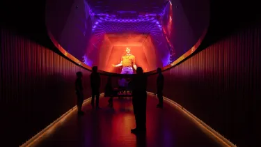 A group of visitors watching a projection of an event on ceiling screens.