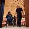 A man escorting a woman on a wheelchair.
