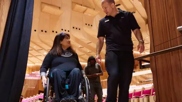 Three people, one in a wheelchair leaving a theatre.