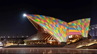 The Sydney Opera House's sails illuminated by colorful squares.